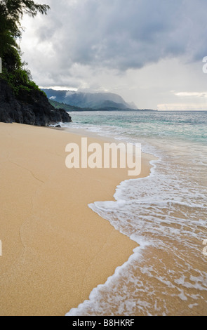 Un burrascoso vista della spiaggia di nascosto con la costa di Na Pali in background sul Nord costa Kauai Hawaii Foto Stock