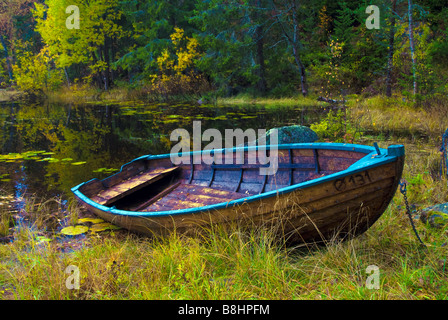 Una barca a remi seduta sul bordo di un laghetto in autunno Foto Stock