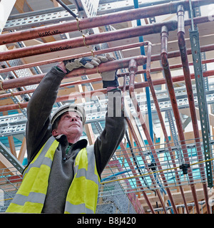 Plumber installando un robusto e duraturo della rete in rame di riscaldamento le tubazioni in un grande edificio comunitario. Foto Stock