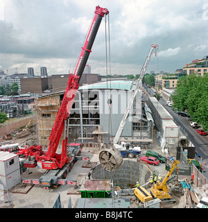 Appaltatori utilizzando mobile gru di sollevamento sezione rotore di taglio dalla macchina di foratura che ha completato lo scavo del cavo di potenza tunnel. Foto Stock