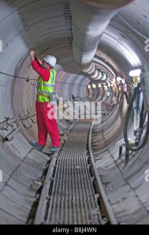 Ingegnere ispeziona i segmenti di calcestruzzo installati in tale avvolgimento del cavo di alimentazione, tunnel scavato da una macchina di foratura di gallerie. Foto Stock