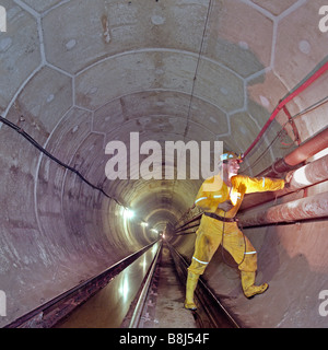 Ingegnere esamina temporaneo di tubazioni in calcestruzzo rivestito sezione del tunnel di acqua, excava ted da una macchina di foratura di gallerie. Foto Stock