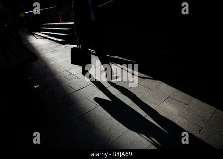 Un imprenditore getta un'ombra mentre camminando attraverso il Mid-livelli in Hong Kong. Foto Stock