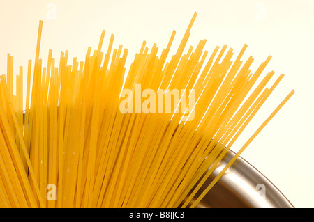 Spaghetti secchi nel piatto di pesata in acciaio inox non cotti acqua grezza cibo italiano carboidrati bolognese arnese da cucina per la cottura white bac Foto Stock