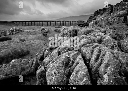 Nuvole temporalesche sulla pavimentazione di pietra calcarea con Ribblehead il viadotto in distanza, Ribblesdale, Yorkshire Dales, North Yorkshire Foto Stock