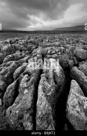 Nuvole temporalesche sulla pavimentazione di pietra calcarea con Ribblehead il viadotto in distanza, Ribblesdale, Yorkshire Dales, North Yorkshire Foto Stock