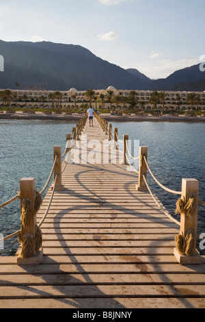 Taba Heights Sinai Egitto pontile in legno in Mar Rosso con vista torna alla spiaggia e hotel resort al di là nel tardo pomeriggio di sole Foto Stock