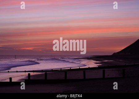 "Norfolk Sunrise' Cromer Beach guardando ad Est verso Overstrand. Pennelli in legno attraversare la spiaggia. Foto Stock