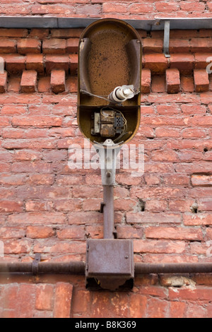 Vecchia Lanterna rotto con shattered lampadina rossa su un muro di mattoni. Foto Stock