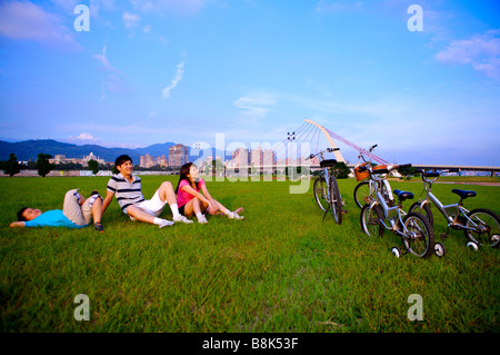 Famiglia con un bambino seduto o disteso sul prato guardando in alto Foto Stock