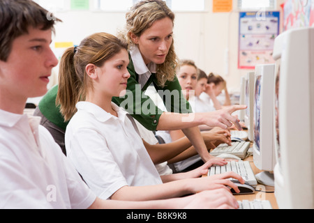 Gli studenti che lavorano su computer workstation con insegnante Foto Stock