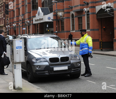 Vigile esecuzione civile Officer a fotografare il disco fiscale di una vettura in Birmingham West Midlands dopo una emissione fissati Foto Stock