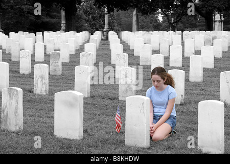 Una giovane ragazza in un cimitero militare in onore di un soldato caduto colorazione selettiva Foto Stock