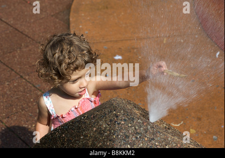 Bambino gioca con un schizzo Fontana in un parco giochi urbano in New York, Stati Uniti d'America Foto Stock