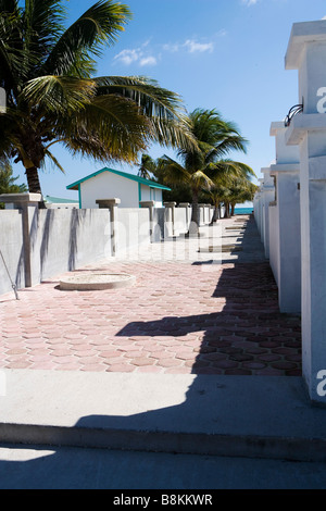 Un passaggio pedonale lastricata conduce il cammino lungo le pareti bianche e le palme per le belle spiagge di Ambergris Caye in Belize. Foto Stock