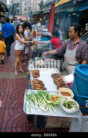 Fornitore di cibo grigliare pollo su un mercato in Chinatown centrale di Bangkok in Thailandia Foto Stock