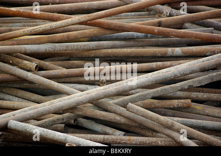 Acciaio, ferro, alluminio aste metalliche e tubi sono accatastati in un cantiere dove il cemento ed il cemento sono versando in costruzione. Foto Stock