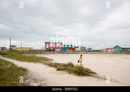 Una giovane ragazza cammina per la sua rosa a due piani di casa su Ambergris Caye nel Belize. Foto Stock