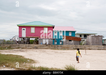 Una giovane ragazza cammina per la sua rosa a due piani di casa su Ambergris Caye nel Belize. Foto Stock