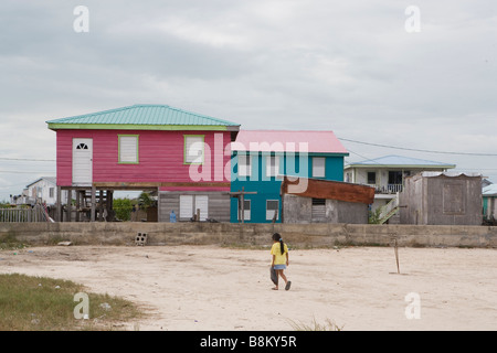 Una giovane ragazza cammina per la sua rosa a due piani di casa su Ambergris Caye nel Belize. Foto Stock