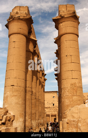 Egitto, Tempio di Luxor, Colonnato di Amenofi III, alti in pietra scolpita colonne di papiro contro nuvoloso cielo blu Foto Stock