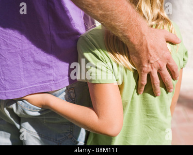 Otto anni ragazza con la mano in tasca posteriore di suo padre che ha braccio protettivo su di lei Foto Stock