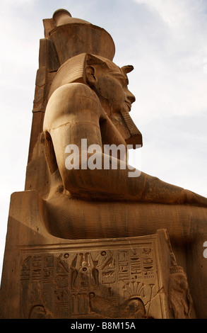 Il colosso del faraone Ramses II seduto sul trono scavato con antichi geroglifici egiziani, grande cortile del tempio di Luxor in Egitto Foto Stock