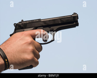 Vista laterale dei maschi di mano che impugna la pistola beretta Foto Stock