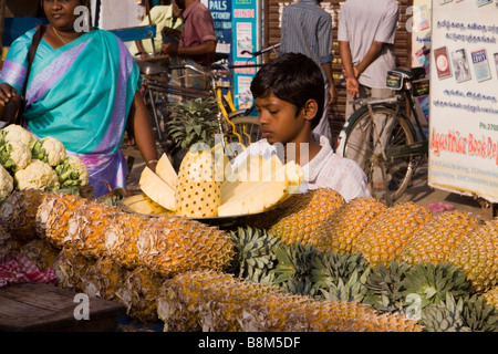 India Tamil Nadu Tiruchirappalli Chinnar Bazaar boy guardando le fette di ananas in stallo del mercato Foto Stock