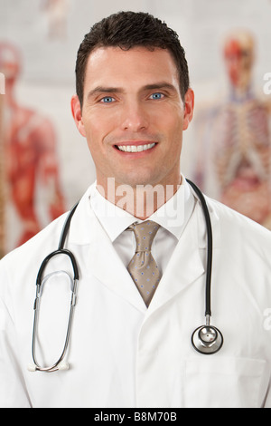 Un medico di sesso maschile con i grafici di medici al di fuori della messa a fuoco dietro di lui Foto Stock