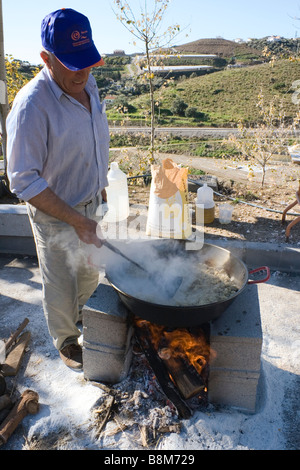 Torrox Pueblo regione Axarquia Malaga Spagna Migas Festival uomo preparando le migas in una grande padella a fuoco di legno Foto Stock