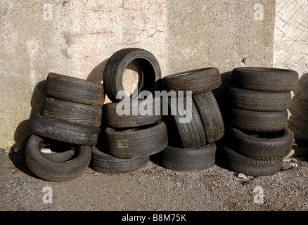 Pneumatici impilati contro una parete del garage. Foto Stock