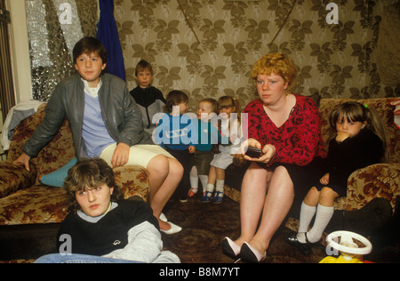 Famiglia madre singola 1980 Regno Unito. Madre che tiene zapper con i suoi sette bambini che guardano la TV a casa. Council estate 1985 Glasgow Scozia HOMER SYKES Foto Stock