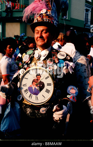 Carnevale di Notting Hill, Londra, Inghilterra: un uomo coperto di badge e pulsanti indossa un gigante Royal Wedding orologio Foto Stock