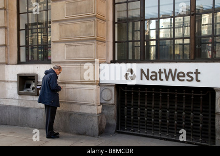 Il cliente il ritiro di denaro da NatWest ATM nella City di Londra Foto Stock