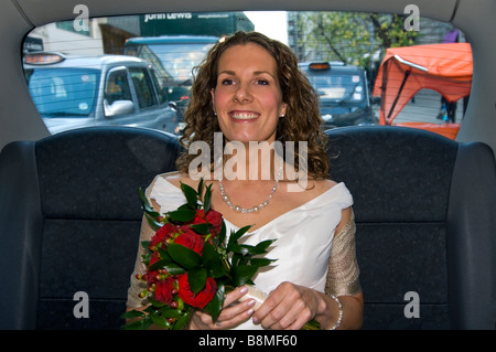 Chiudere orizzontale su ritratto di una bella sposa in un tradizionale abito bianco che viaggiano nel retro di un taxi neri di Londra Foto Stock