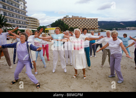 Gruppo di anziani persone mantenendo montare giovani nel cuore British seniors il inverno vacanze in Isole Baleari Palma Nova Maiorca Spagna. Anni ottanta HOMER SYKES Foto Stock