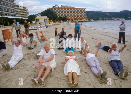 Gruppo di anziani persone mantenendo montare giovani nel cuore British seniors il inverno vacanze in Isole Baleari Palma Nova Maiorca Spagna. Anni ottanta HOMER SYKES Foto Stock