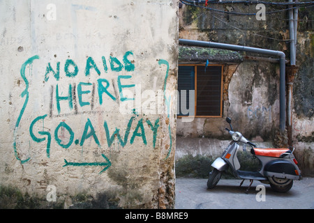 AIDS slogan i graffiti sulla parete e uno scooter nel centro storico dell'UNESCO elencati di Stone Town a Zanzibar, Tanzania Foto Stock