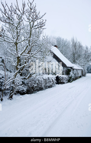 Scena di neve di un viottolo di campagna nel Buckinghamshire con un cottage con tetto di paglia Foto Stock