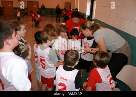 Coach incarica il giovane squadra di basket durante una partita (età 5-7) Stati Uniti, gruppo di bambini in palestra pubblica Foto Stock