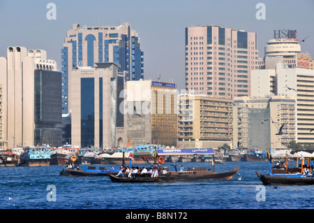 Dubai riverside skyline e moderni edifici grattacielo & architettura accanto a Dubai Creek occupato con Abras acqua taxi per il trasporto di passeggeri negli EMIRATI ARABI UNITI Asia Foto Stock