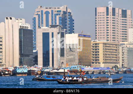 Trasporto in Dubai edificio moderno architettura Dubai Creek grattacielo lungo il fiume Skyline e affollato con Abras taxi d'acqua passeggeri UAE Middle Asia orientale Foto Stock