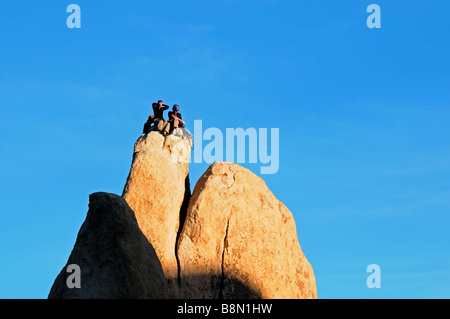 Tre arrampicatori l uomo e la donna sempre pronto a scendere dalla parte superiore di un pinnacolo di roccia Hidden Valley Joshua Tree National Park Foto Stock