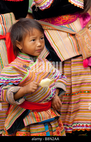 Ritratto di un fiore H'mongs ragazza vestita in costume tradizionale della minoranza etnica in gruppo Bac Ha, Vietnam. Disegni tribali decorano il costume Foto Stock