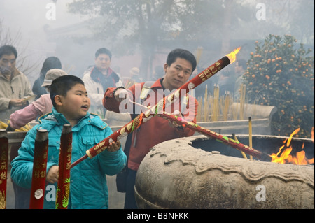 Uomo e per ragazzo grande luce bastoncini di incenso al Monastero Po Lin su foggy primo giorno del nuovo anno lunare 2009 Lantau Hong Kong Foto Stock