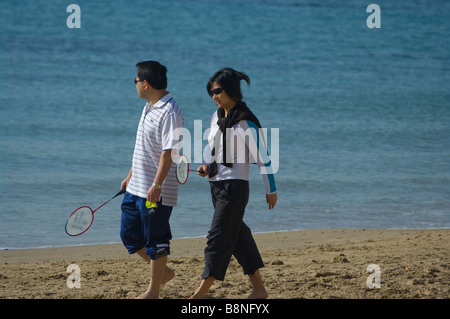 Oriental coppia giovane camminando lungo la spiaggia spiaggia Foto Stock