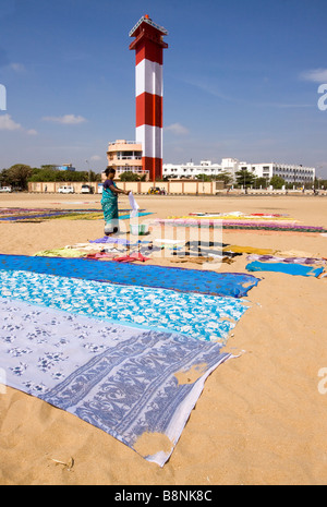 India Tamil Nadu Chennai donna asciugatura biancheria colorata sulla spiaggia sotto il faro Foto Stock