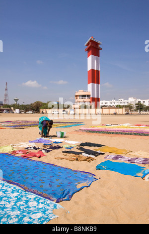 India Tamil Nadu Chennai donna asciugatura biancheria colorata sulla spiaggia sotto il faro Foto Stock