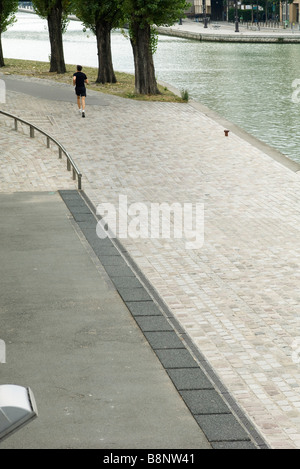 Francia, Parigi, Canal Saint-Martin, persona fare jogging lungo il bordo d'acqua Foto Stock